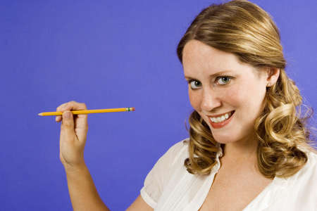 Woman on blue holding pencil out to blank spaceの写真素材