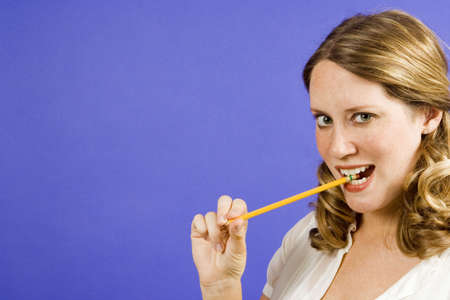 Woman on blue biteing a pencilの写真素材