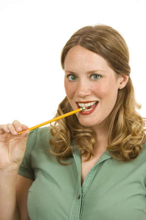 Young woman on white biteing a pencilの写真素材