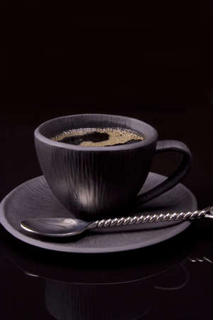 Black tea cup on black background with spoonの写真素材