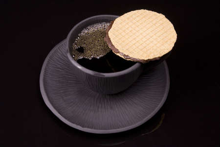 Black tea cup on black background with cookieの写真素材