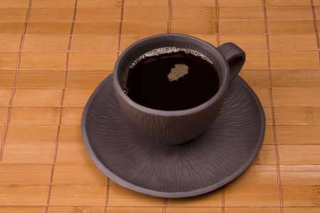 Black mug of coffee on brown backgroundの写真素材