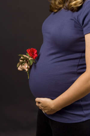 Pregnant woman on white background holding a flowerの写真素材
