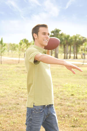 Attractive young man outside holding an american football