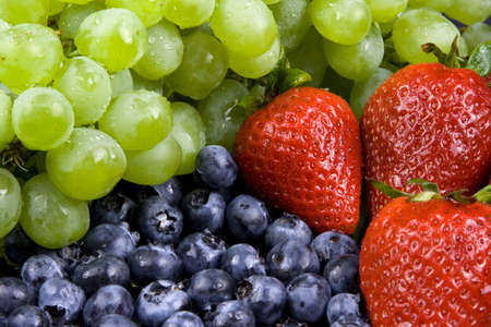 Assorted fruits on a black background. Grapes blueberries and strawberries.の写真素材