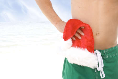 Man holding santa hat at the beach.の写真素材