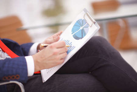 Discussing the scheme. Side view of business people, pointing handles on the chart together, sitting at the tableの写真素材