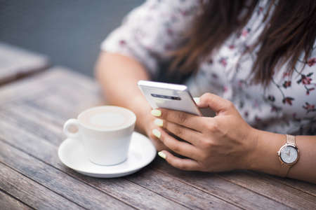 Close up of womens hands holding mobile phone with blank copy space screen for your advertising text message or promotional content.の写真素材
