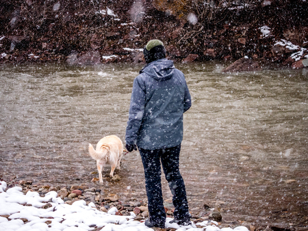 Woman and her Labrador  at a river in snow stormの写真素材