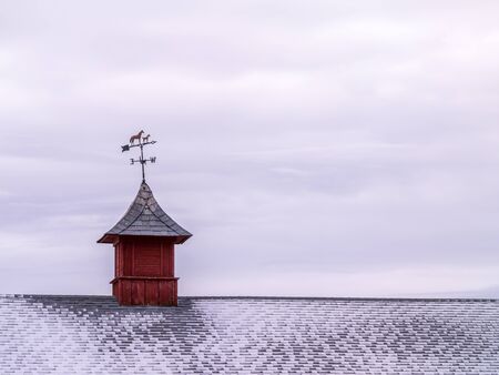 Metal weather vane with horses over snowy, shingles roofの写真素材