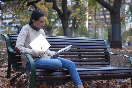 Writing in book on park benchの写真素材