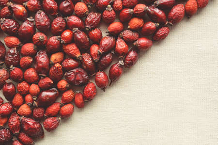 Backgroung with dried dog rose hips diagonally positioned on a light beige canvasの写真素材