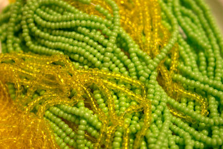 This is a closeup photograph of Green and Yellow Glass seed beads backgroundの写真素材