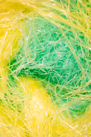 This is a photograph of Green and Yellow shredded plastic fake Easter grass backgroundの写真素材