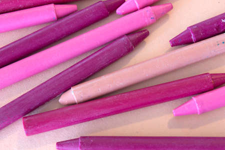 This is a photograph of Pink and Purple crayons on a colorful craft paper background
