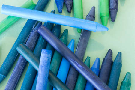 This is a photograph of Blue,Green and Purple crayons placed on colorful craft paperの写真素材