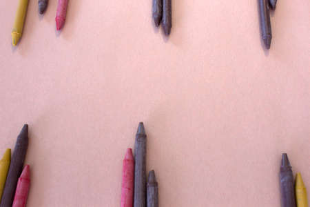 This is a photograph of Brown,Yellow and Red crayons placed on colorful craft paper backgroundの写真素材
