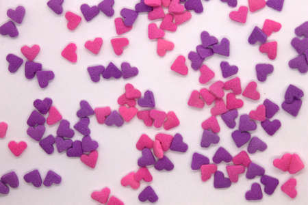 This is a photograph of Pink and Purple heart sprinkles isolated on a White background
