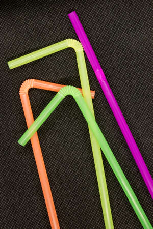 This is a photograph of Colorful Plastic Straws isolated on a textured Black background