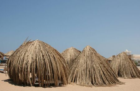 Tents from leaves of palm trees cost on a beach at the seaの写真素材