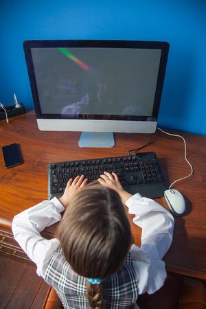 the girl is sitting at the table and working and studying at the computerの写真素材