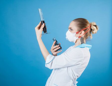 beautiful woman doctor in protective mask against coronavirus on a blue background in the Studio