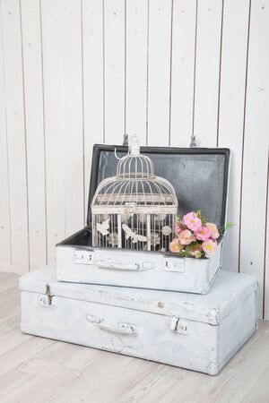 two antique white suitcases against a white wooden wallの写真素材
