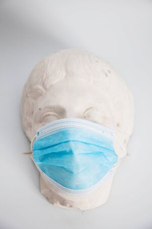Blue protective medical mask worn on an old Roman statuの写真素材
