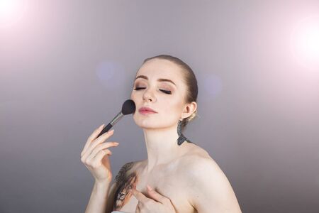 beautiful girl with healthy skin relaxes after a Spa and applies makeup with a brushの写真素材