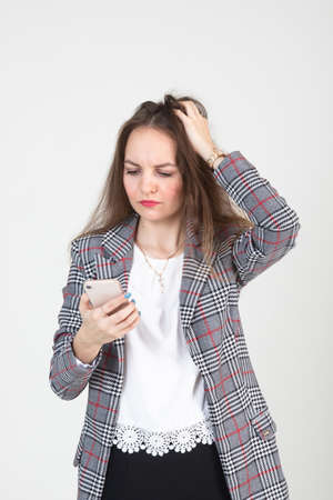 A disgruntled young woman is talking on the phone on a white backgroundの写真素材