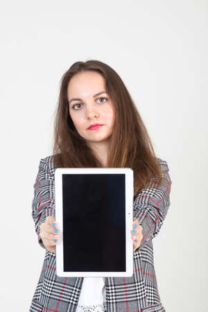 beautiful young woman in business strict clothes demonstrates the tablet screen with business informationの写真素材