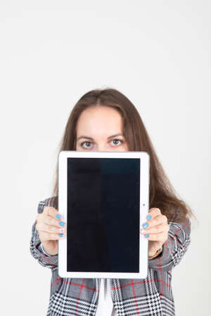 beautiful young woman in business strict clothes demonstrates the tablet screen with business informationの写真素材
