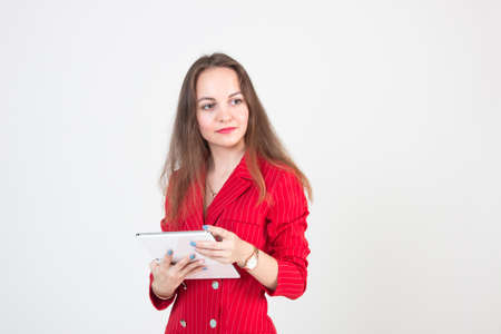 Portrait of a young business woman with beautiful eyes in a red suit and a tablet in her handsの写真素材