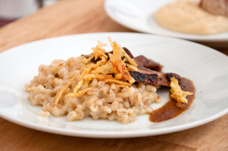 Serving plate with roasted meat, pearl barley and roasted onionsの写真素材