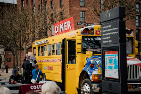 Liverpool, UK, April 11 2024: The yellow bus transformed into a food truck, from the Albert Dock, serves food to passers-by visiting the city of Liverpool, near the M&S Bank Arena.のeditorial素材