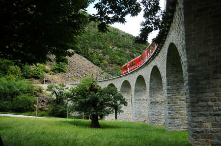 Switzerland: July 2012, Swiss Red Train Bernina Express passes on Buzz Viaduct, Italy & Switzerland