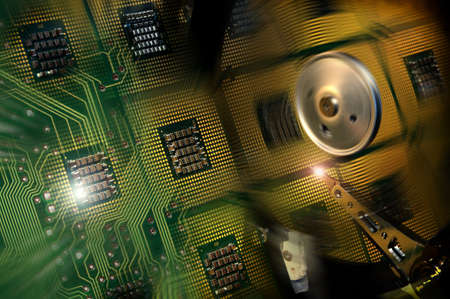 Aligned Processors CPUs and green electronic circuits reflected on open hard drive disk. background
