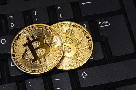 close up of cryptocurrency phisical bitcoin over computer keyboard. concept business financial image