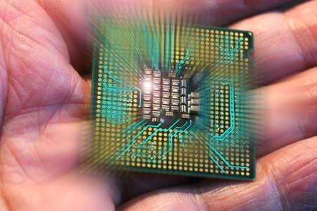 Hand holding a CPU Processor Chip from a PC with electronic circuit effectの写真素材