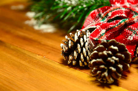 Red bow with fir tree branch and snowy pine cones on wooden background. Christmas background. Xmas...