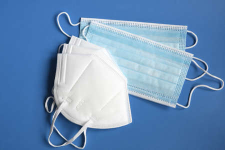 White KN95 or N95 mask with antiviral medical mask for protection against coronavirus on blue...