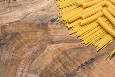 Pasta, spaghetti and celery on an olive wood cutting board.