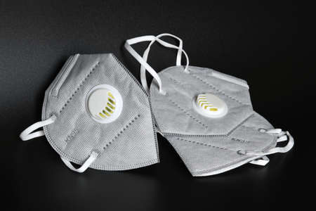 KN95 or N95 mask with valve for protection pm 2.5 and corona virus on black background. Prevention of the spread of virus and pandemic COVID-19.の写真素材