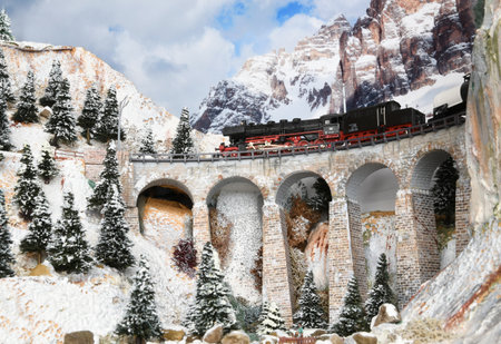 Florence, ITALY- October 2020: Model railway with steam locomotive model train on viaduct. Winter ambientation.のeditorial素材
