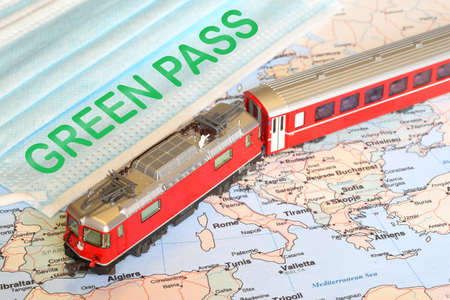 surgÃ¬cal masks with text GREEN PASS over a geographical map and a model of red train. Safe travel concept during Coronavirus with Green passの写真素材