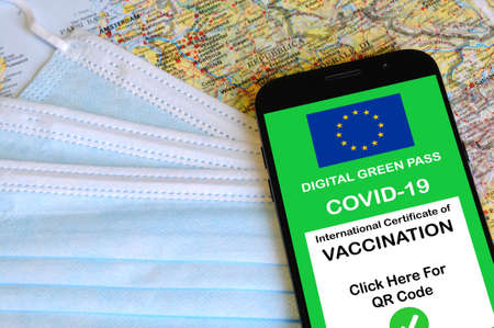 The digital green pass of the European Union with the QR code on the screen of a smartphone. Covid or Coronavirus vaccine certificate, with mask and map of Europeの写真素材