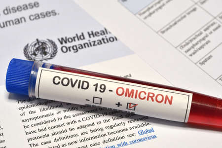 Florence, December 2021: Blood tube for test detection of virus Covid-19 Omicron Variant with positive result on papers document.のeditorial素材