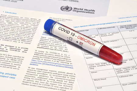 Florence, December 2021: Blood tube for test detection of virus Covid-19 Omicron Variant with positive result on papers document.のeditorial素材