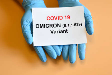 Covid-19 new Omicron variant. The hands of the doctor in blue gloves hold a white paper with the inscription "Covid-19 variant Omicron".の写真素材