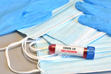 Blood tube for test detection of virus Covid-19 Deltacron Variant with positive result on protective masks.の写真素材